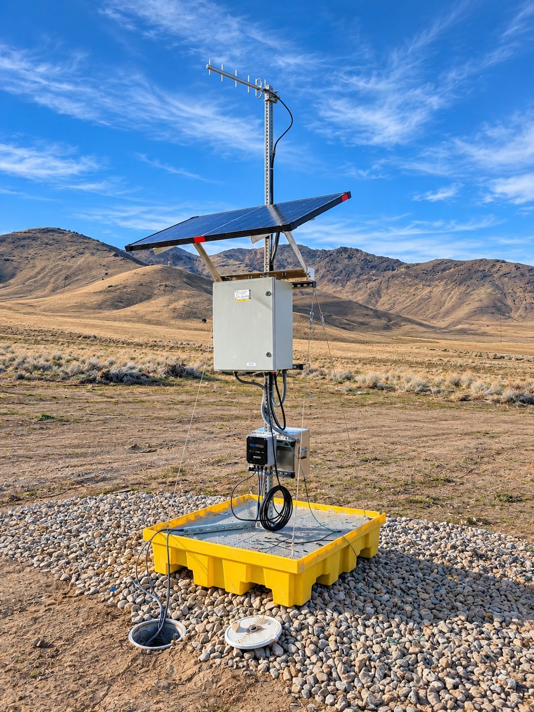 Autonomous solar-powered groundwater and water quality monitoring station on a yellow containment base